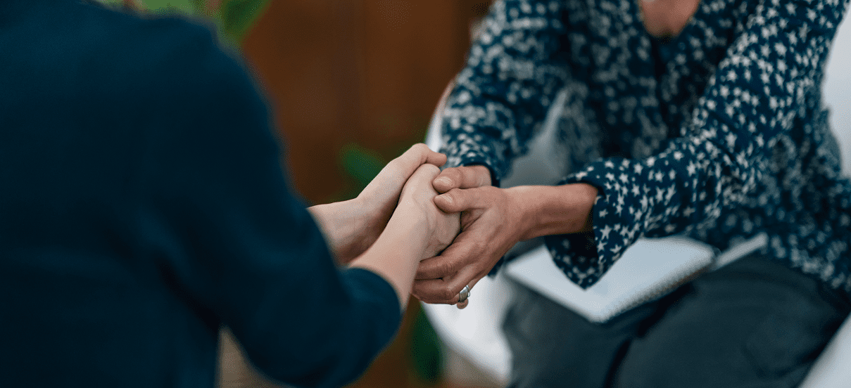 Two people holding hands in support.