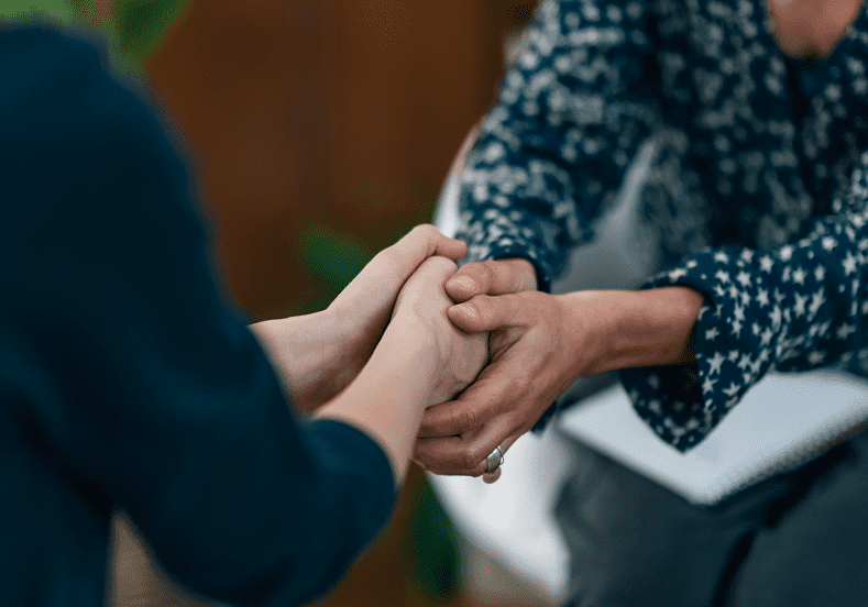 Two people holding hands in support.